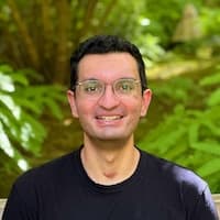 A photo of Aaroh, smiling at the camera with a forest background.